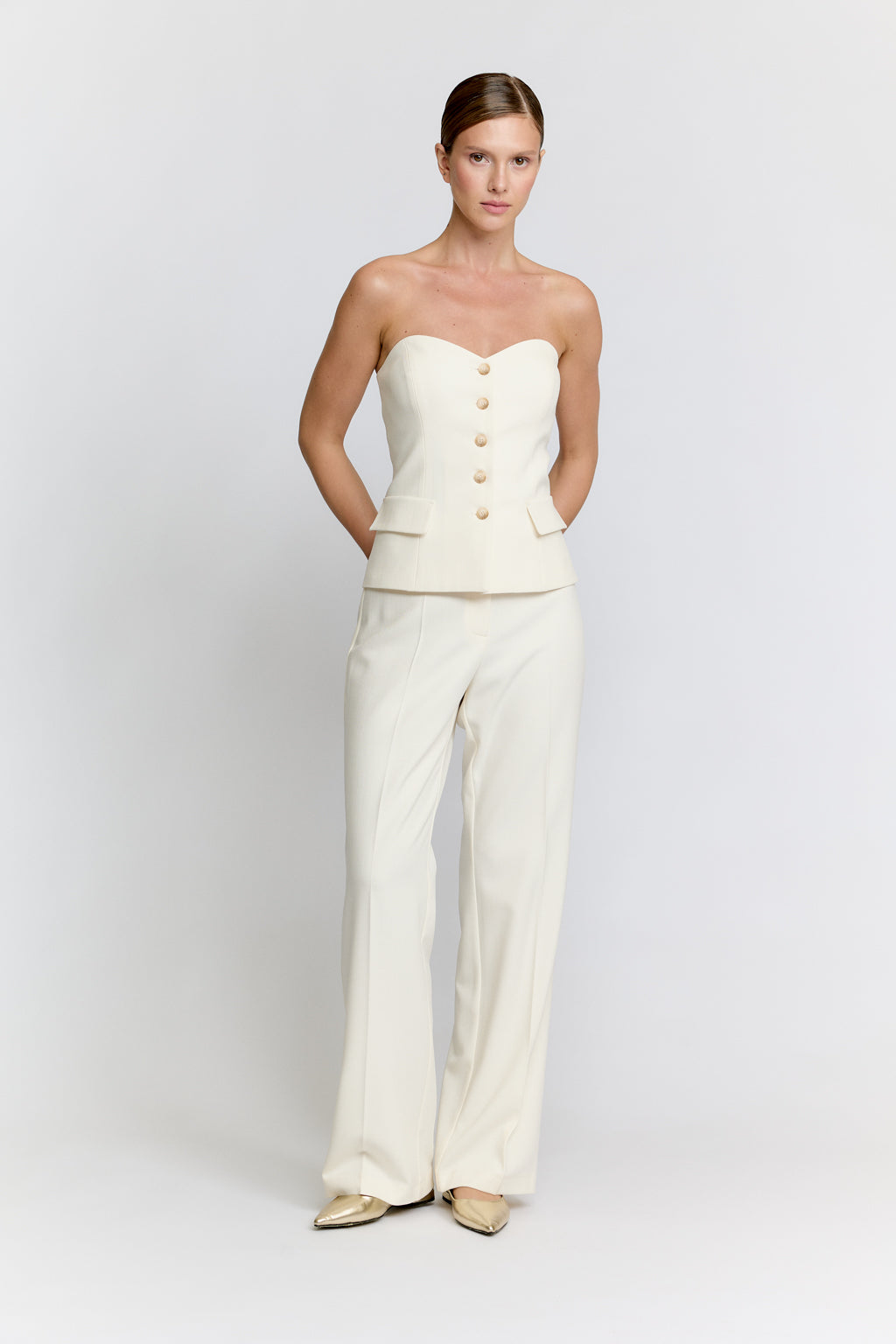 Woman wearing a strapless top and wide-leg pants on a plain background