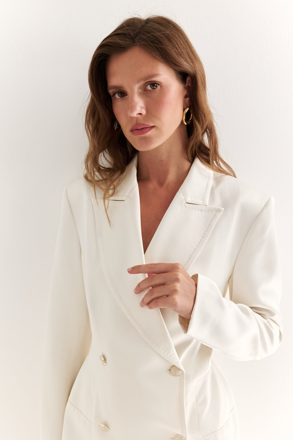 Woman wearing a white blazer against a plain background