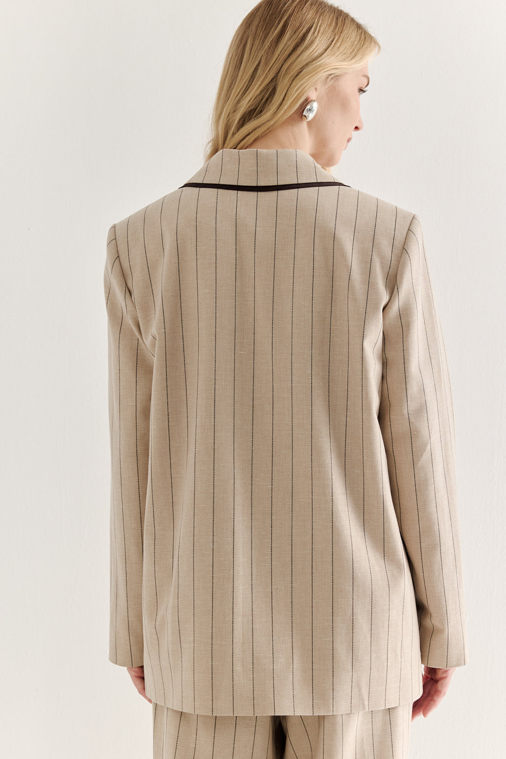 Woman wearing a beige pinstripe suit against a white background