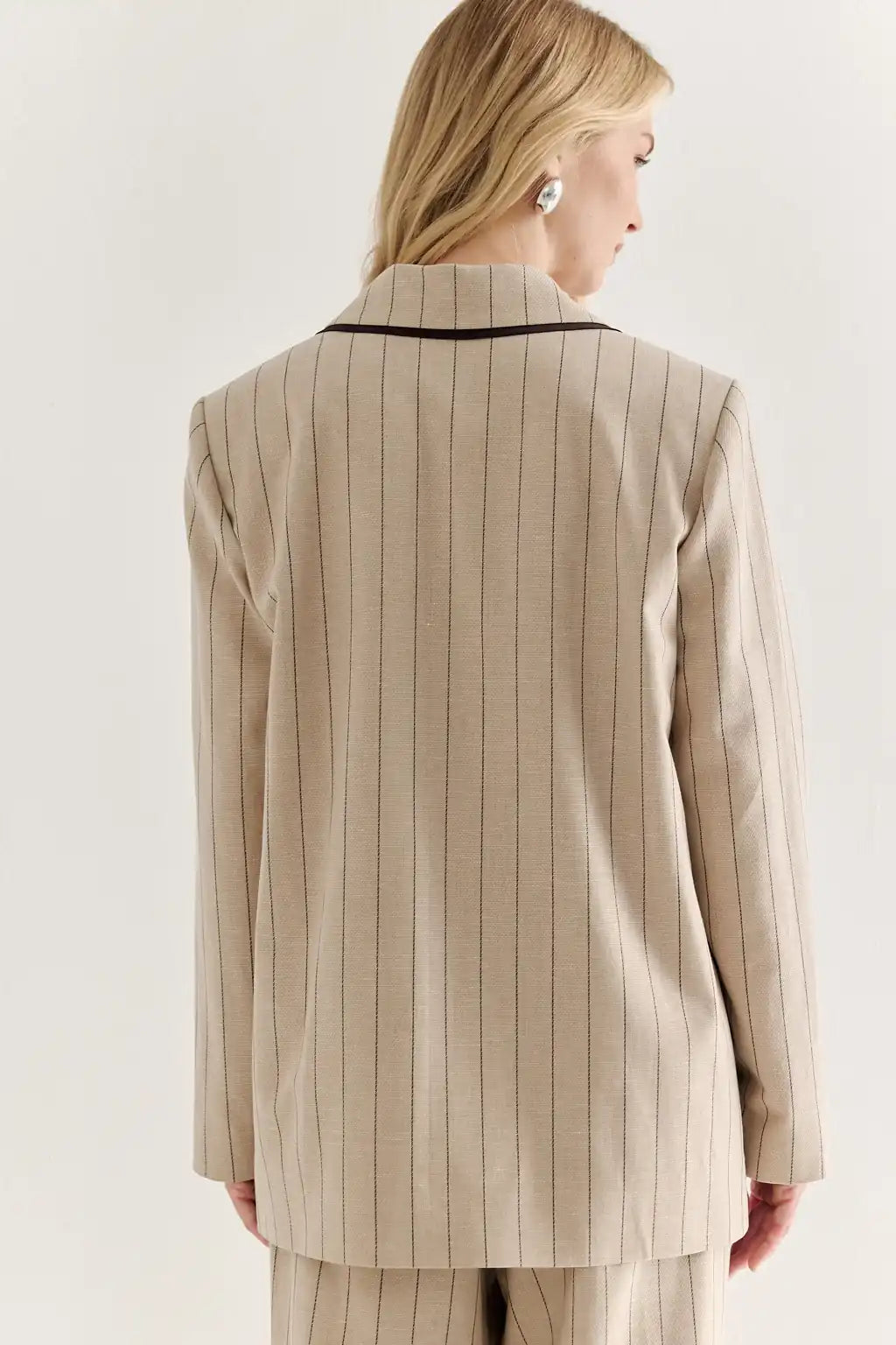 Woman wearing a beige pinstripe suit against a white background