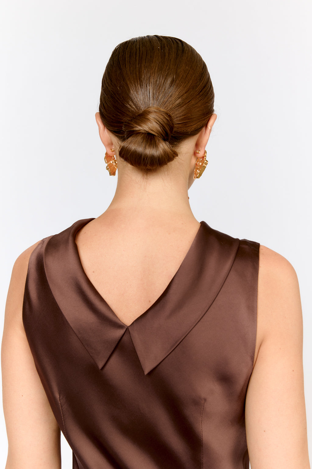 Woman wearing a brown dress with a large collar against a white background