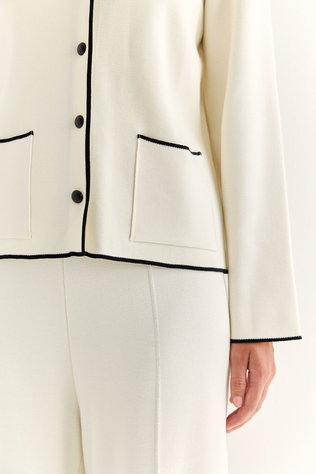 Close-up of a white outfit with black piping on a white background