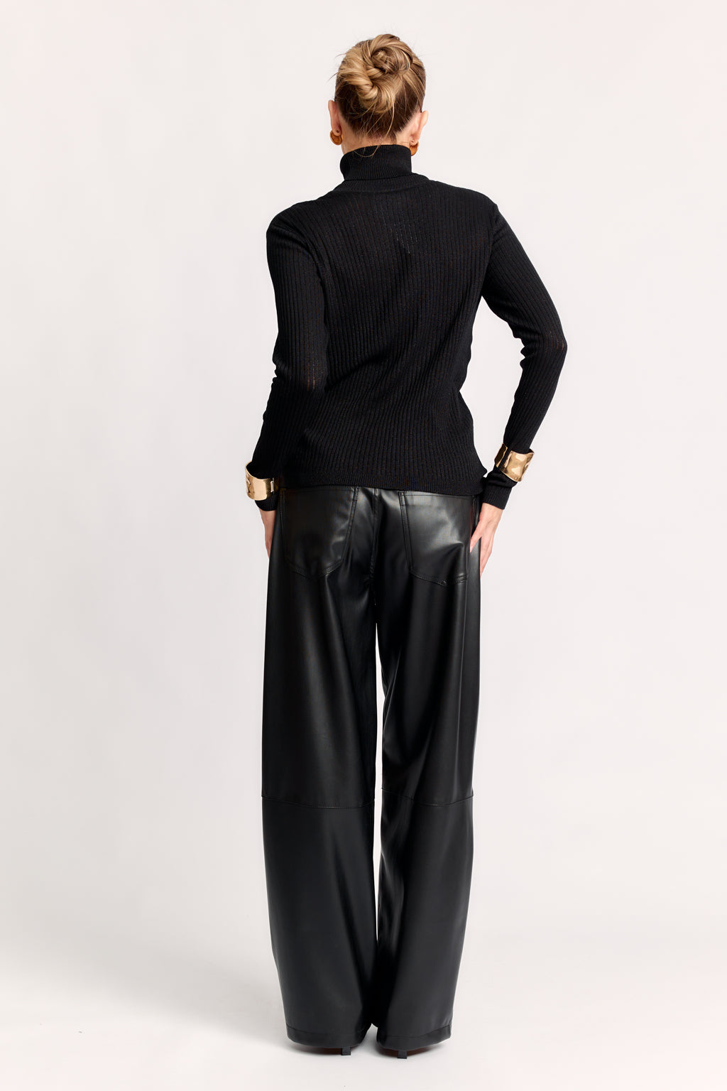 Person wearing a black turtleneck and leather pants on a white background