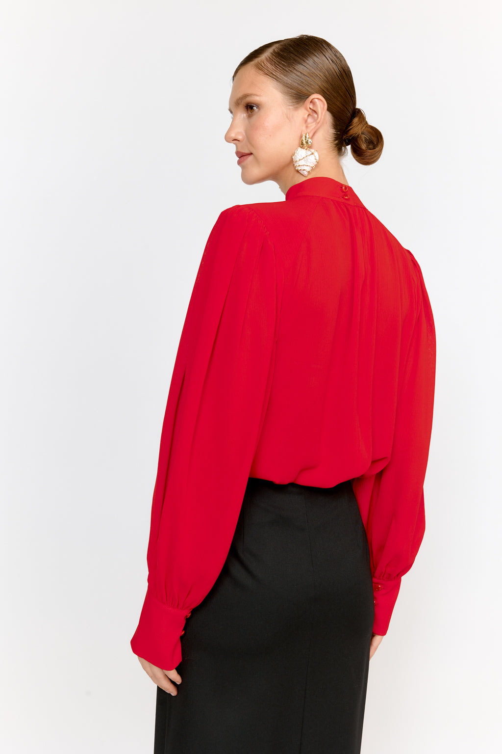 Woman wearing a red blouse and black pants on a white background