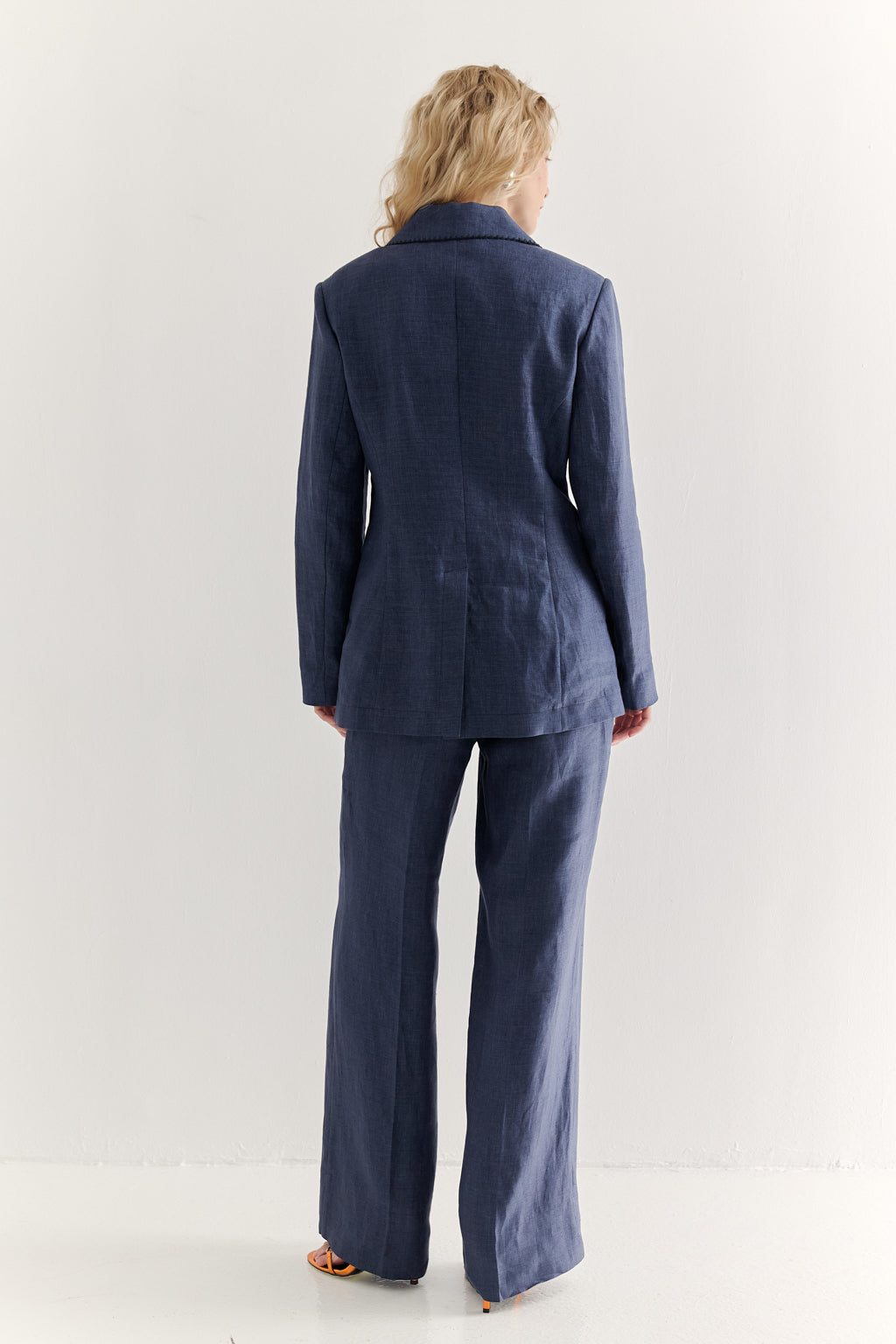 Person wearing a navy blue suit standing against a white background
