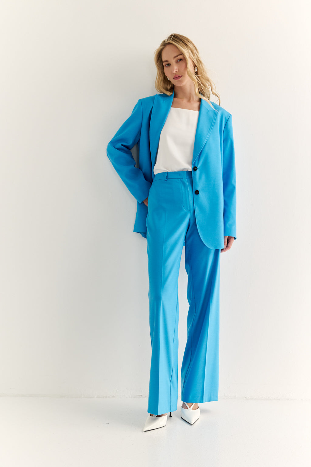 Woman wearing a bright blue suit with a white top on a light gray background