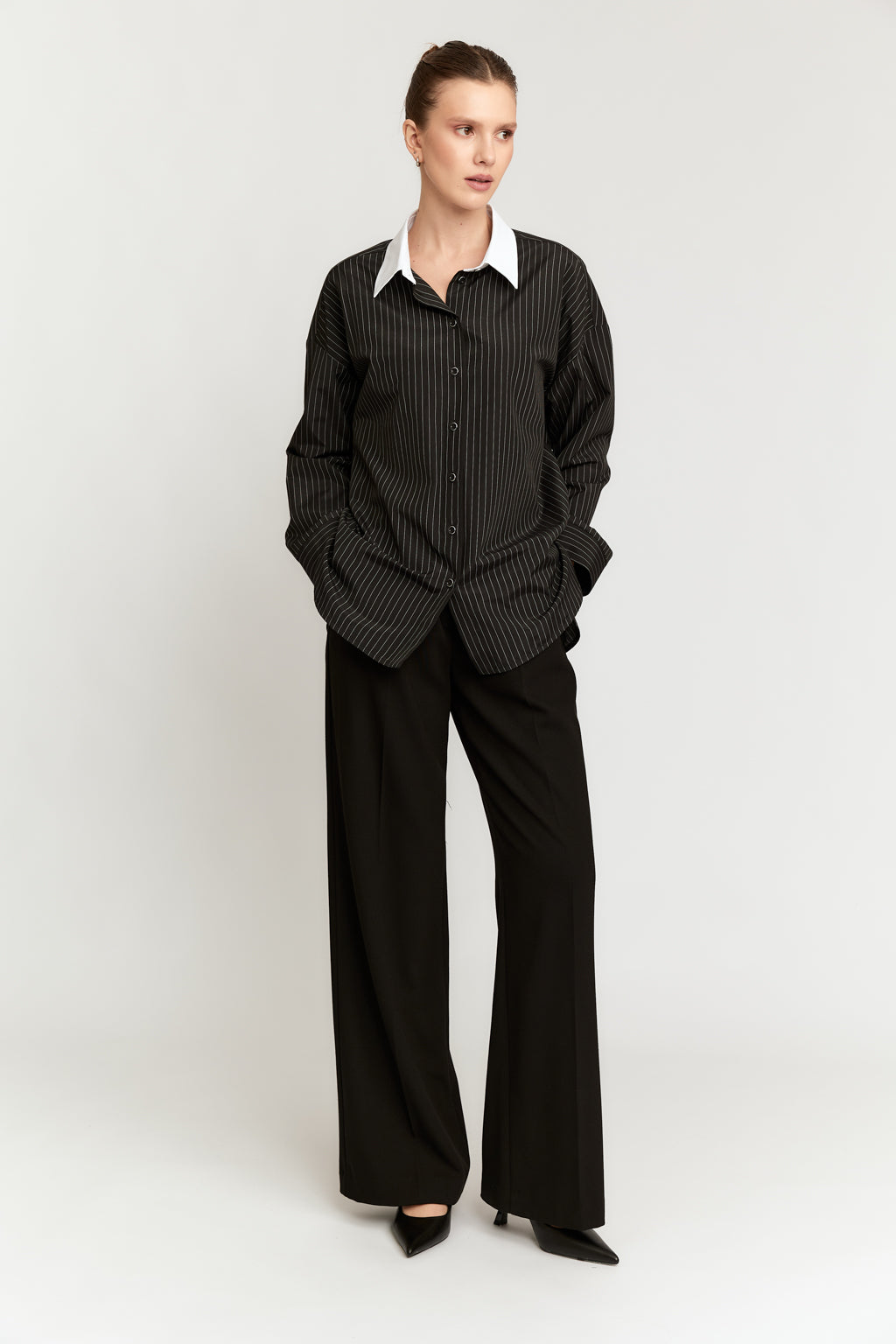 Person wearing a black checkered shirt and black pants on a white background