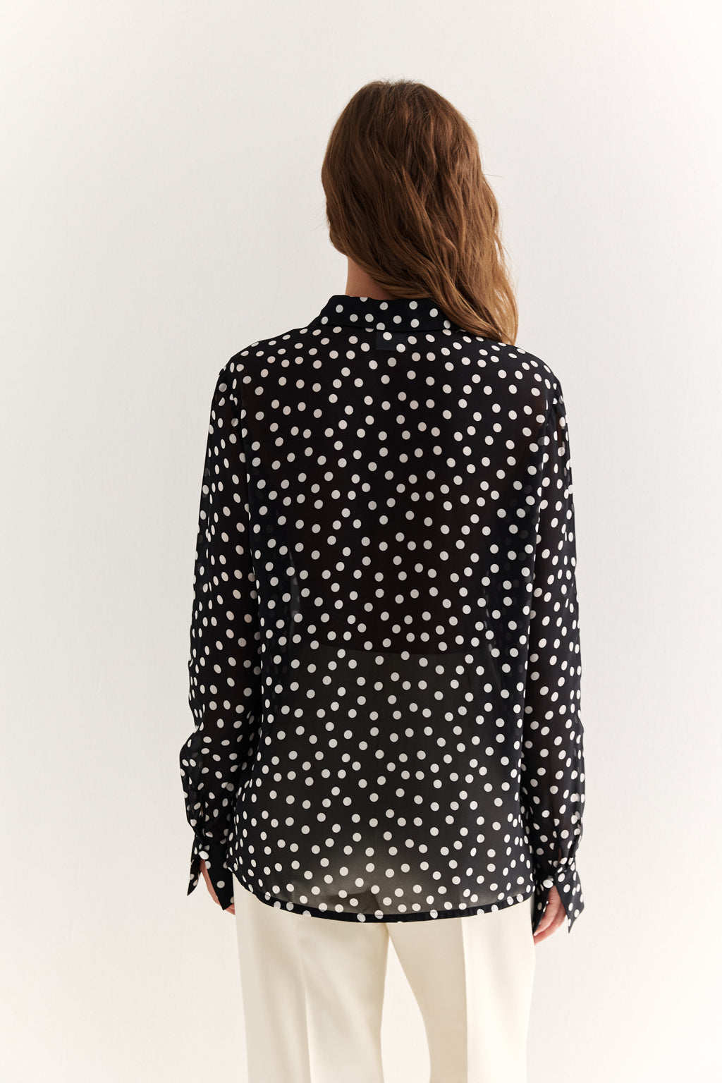 Person wearing a black polka dot shirt on a white background
