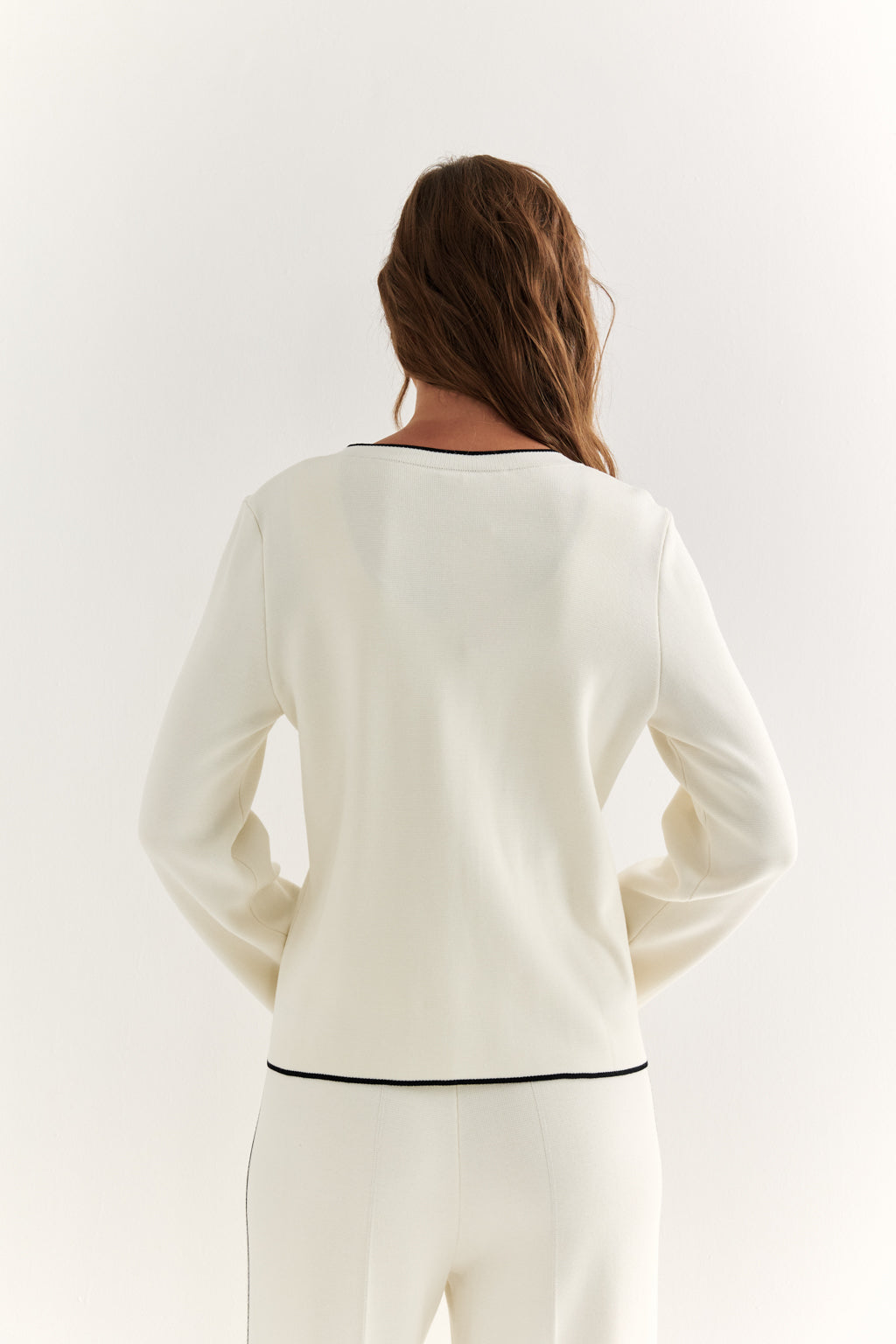 Woman wearing a white long-sleeve top with a black trim on a white background