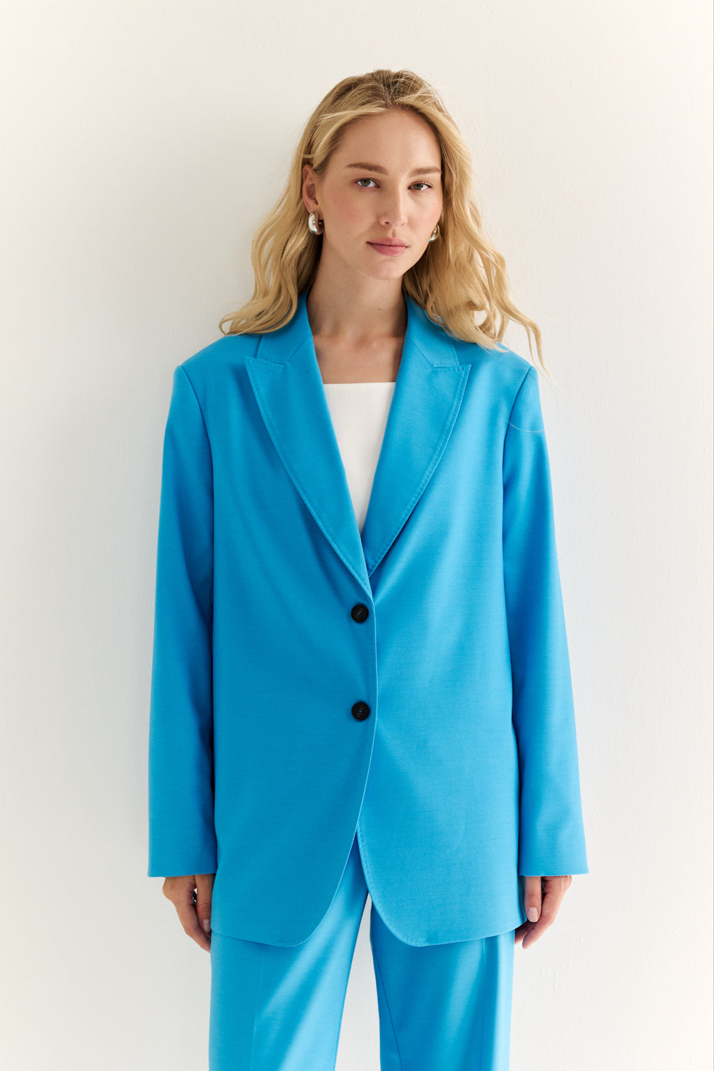 Woman wearing a bright blue suit against a white background