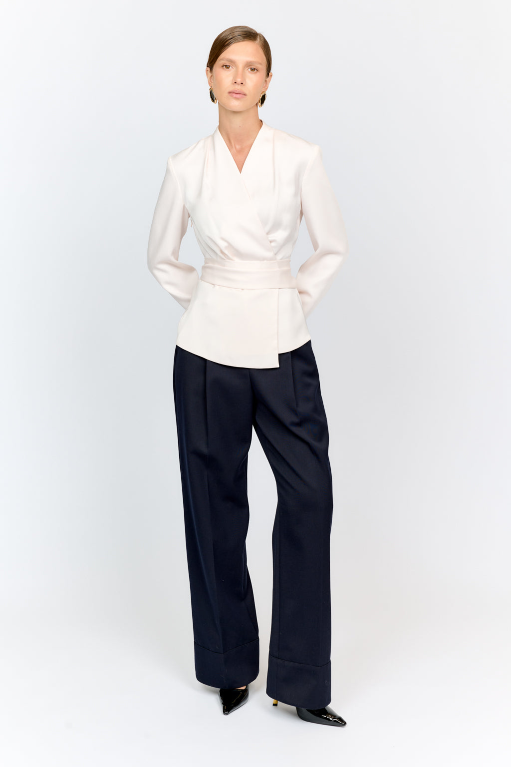 Person wearing a white blouse and black pants on a white background