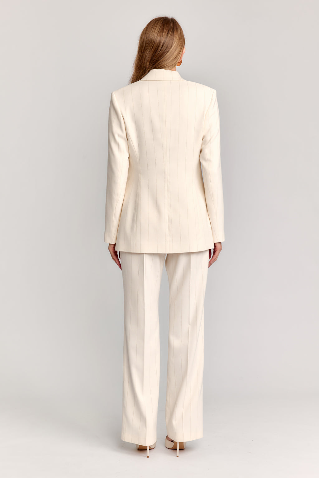 Woman wearing a beige suit on a light gray background