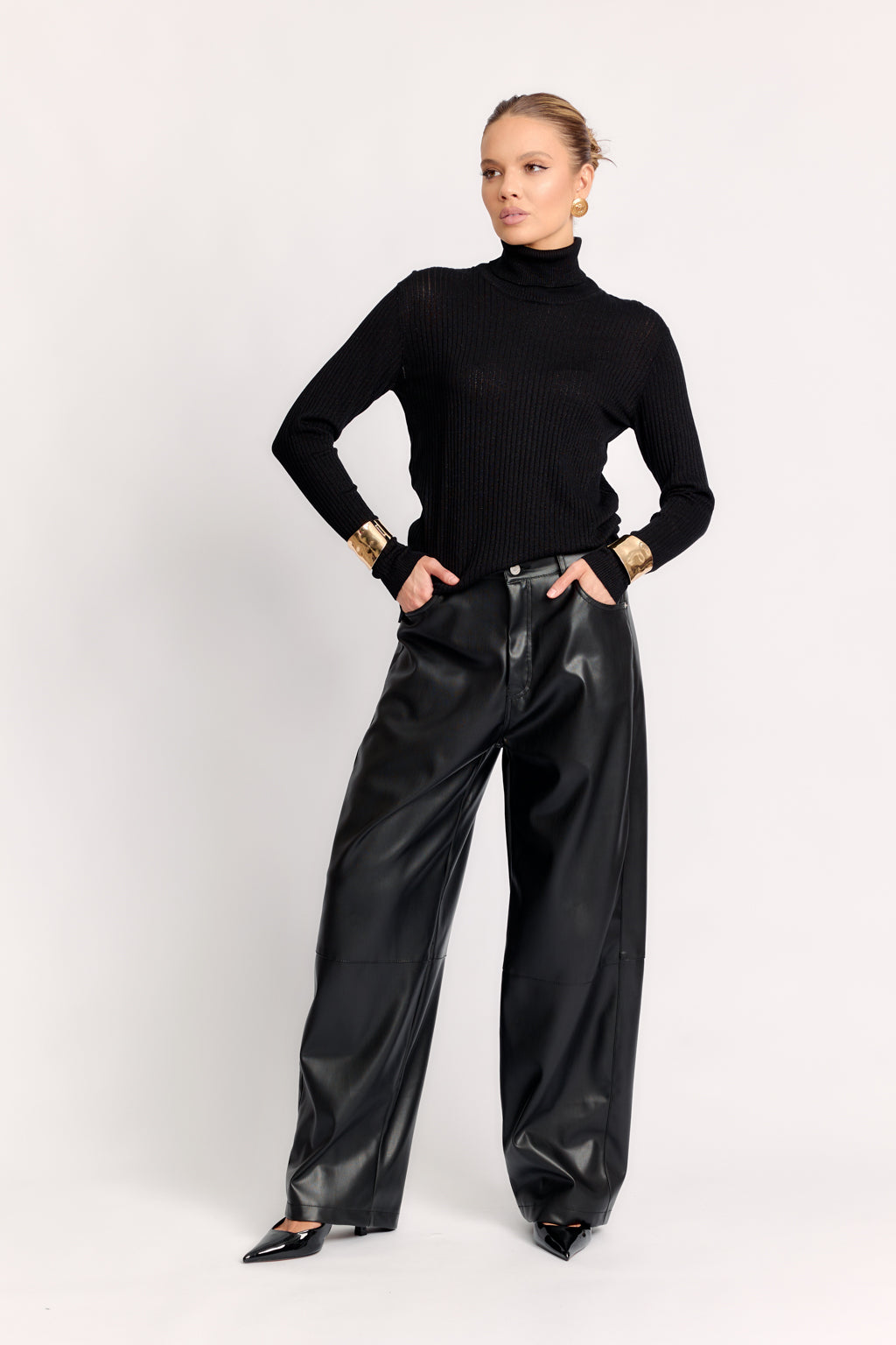 Person wearing a black turtleneck and black leather pants on a white background
