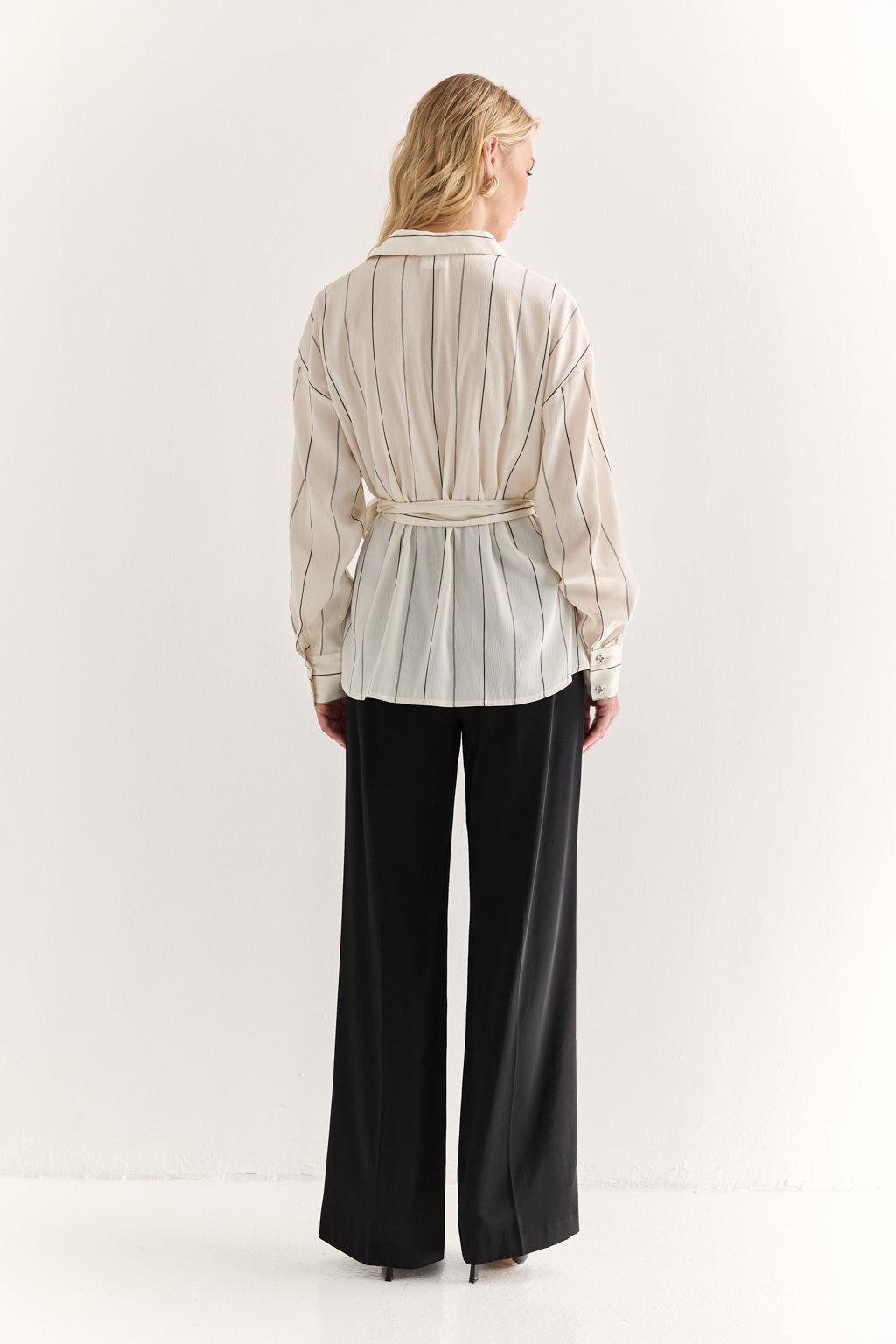 Woman wearing a striped shirt and black pants on a white background