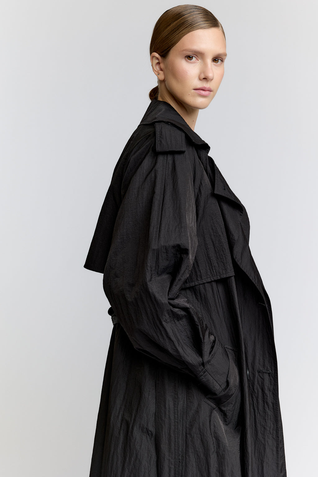 Woman wearing a black coat on a light gray background