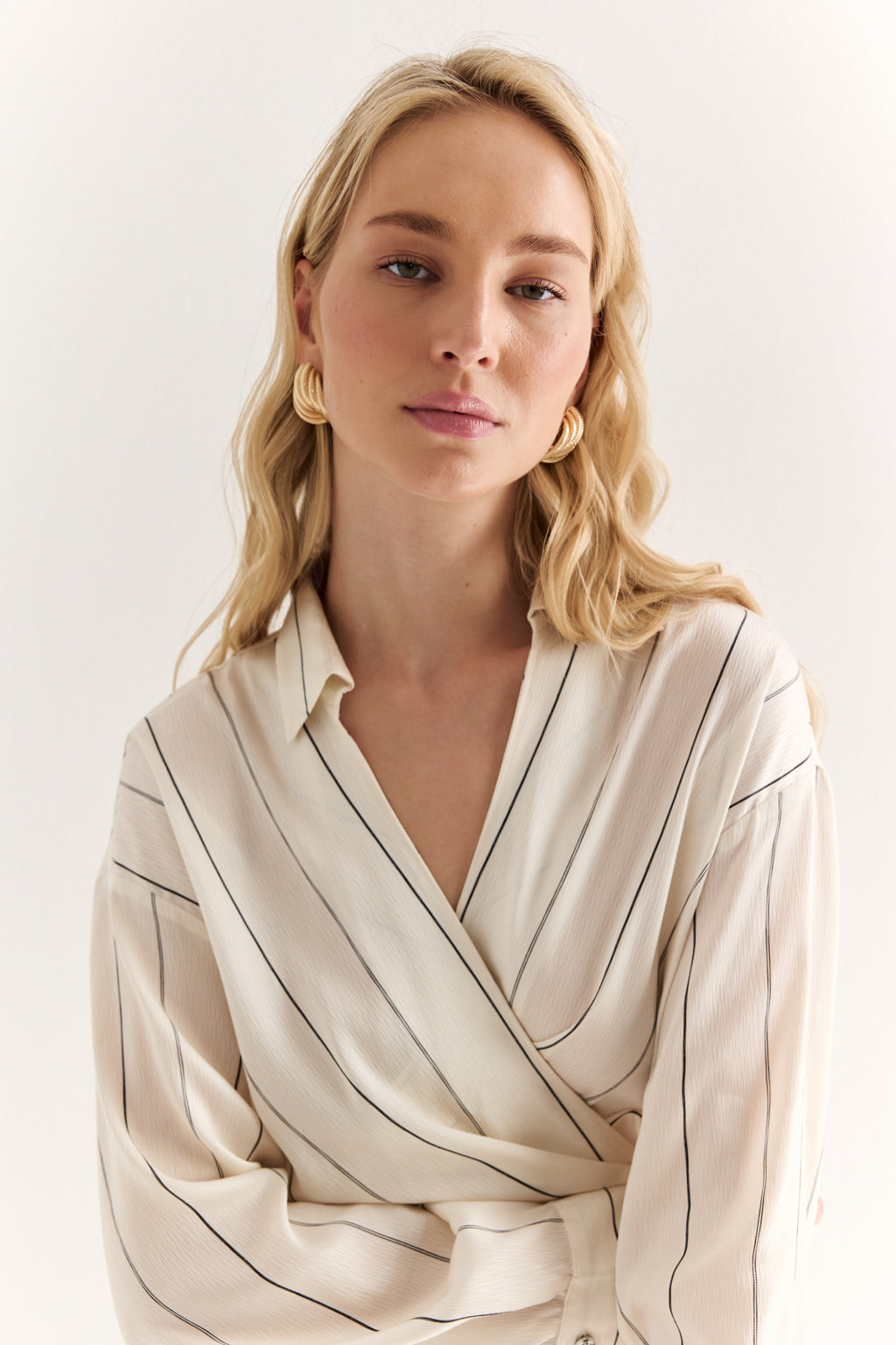 Woman wearing a beige striped blouse against a white background