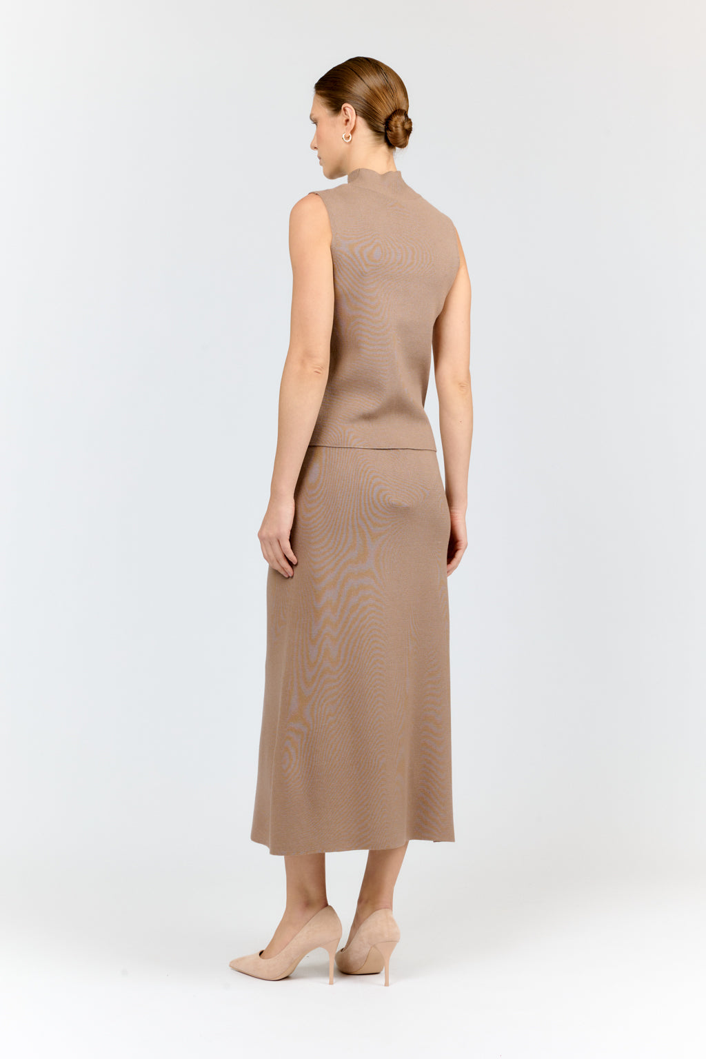 Woman wearing a beige sleeveless dress on a white background