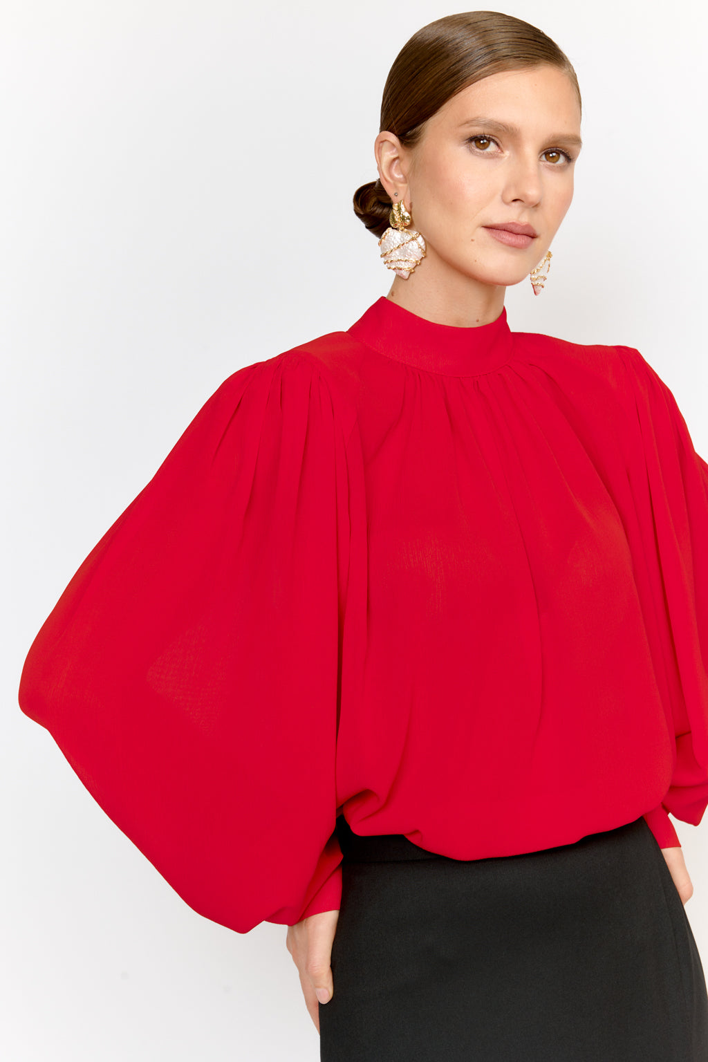 Woman wearing a red blouse with puffed sleeves on a white background