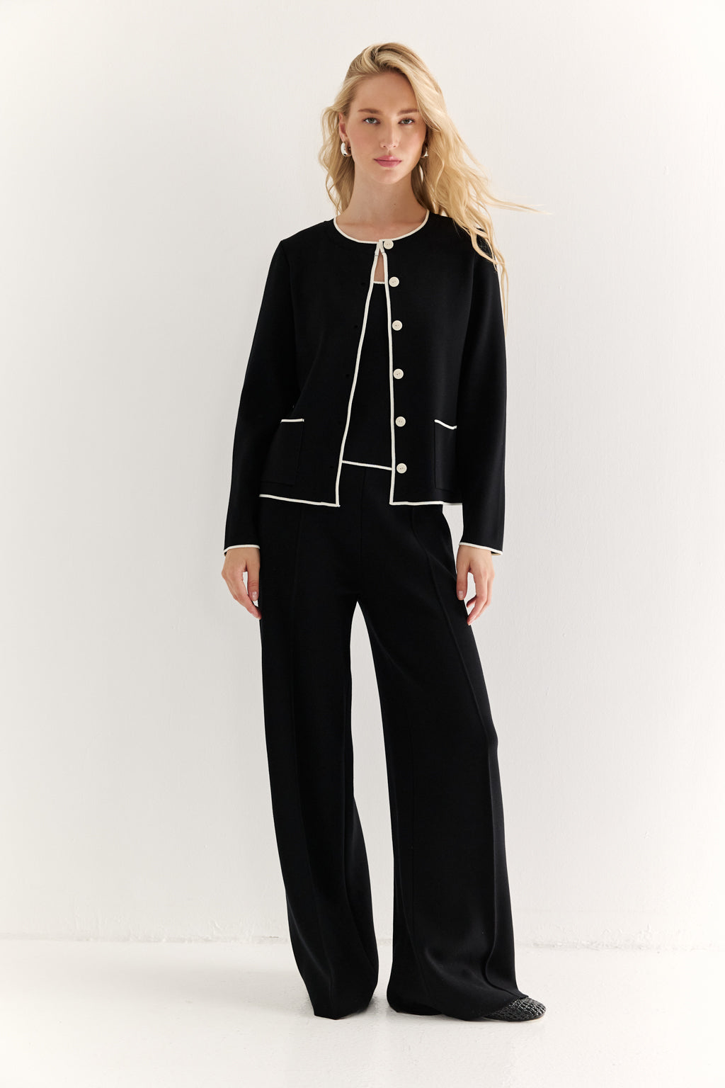 Woman wearing a black suit with white trim on a white background