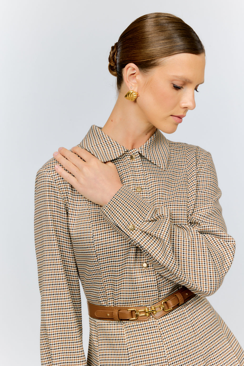 Woman wearing a patterned dress with a belt against a light background