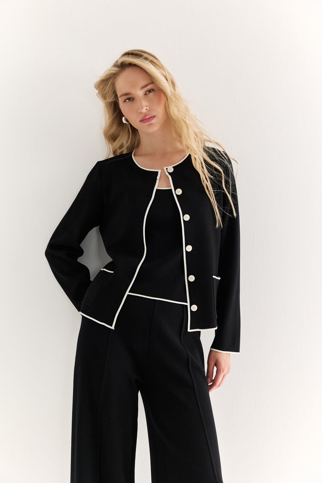 Woman wearing a black outfit with white buttons against a white background