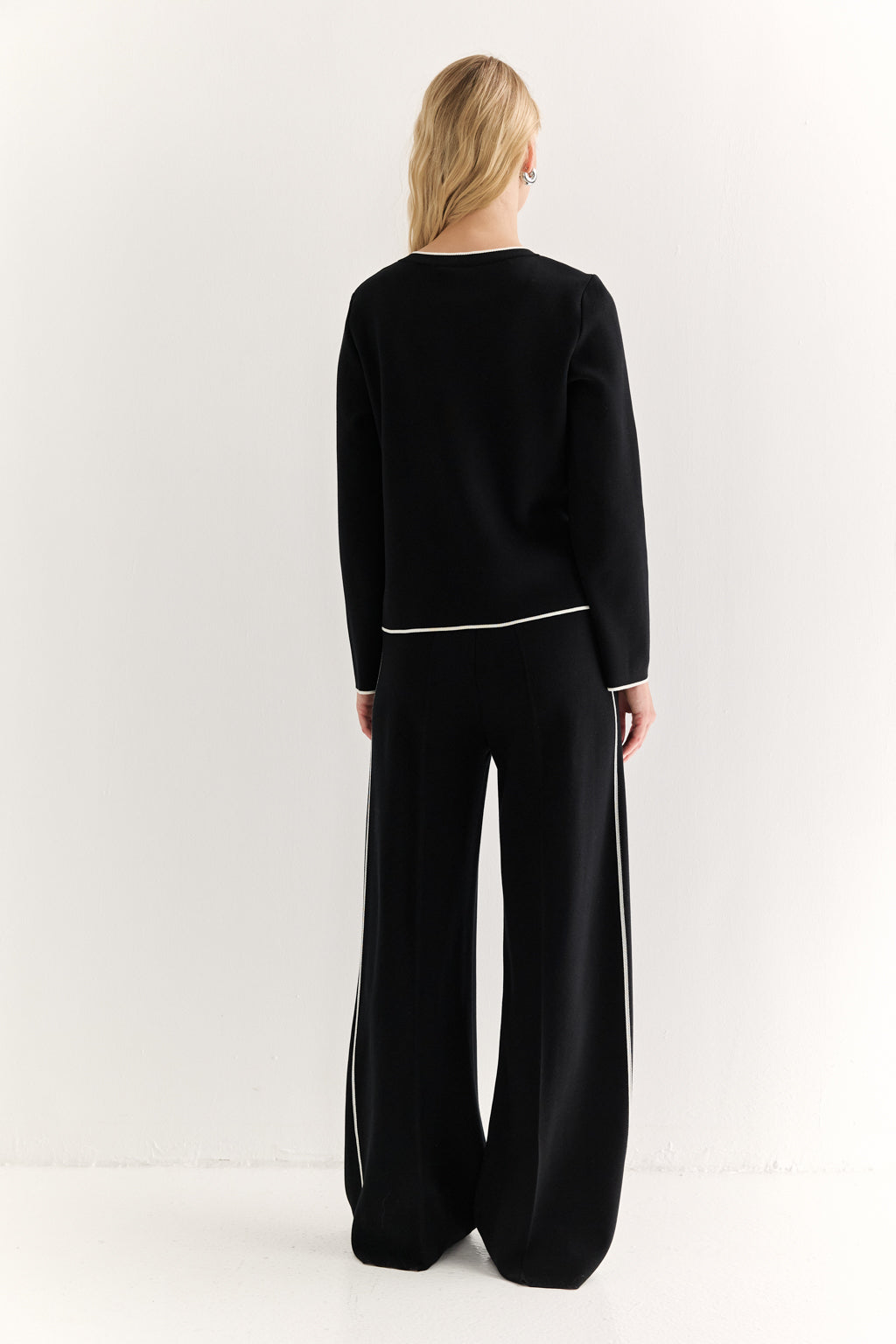 Person wearing a black outfit with white stripes on a white background