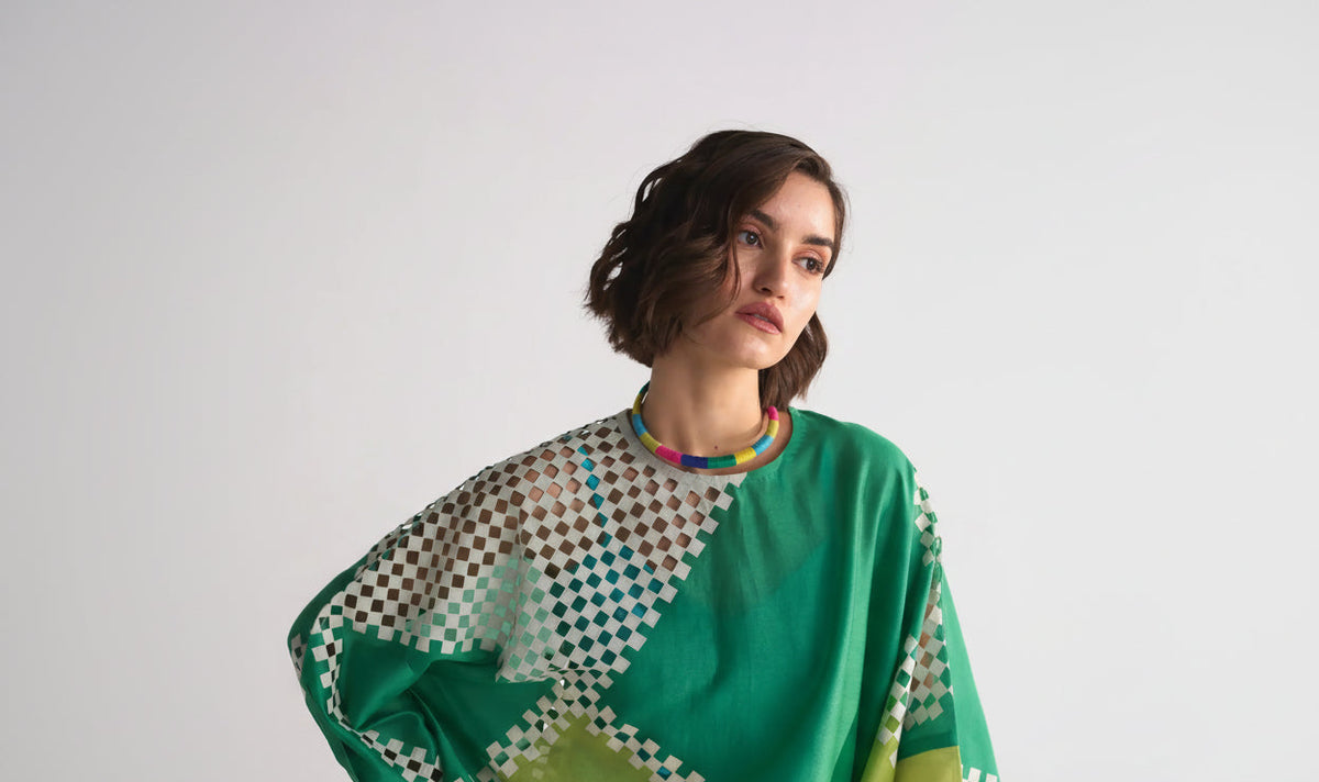 Woman wearing a green and patterned sheer top against a white background, ayra store , luxury sustainable women fashion brand promotes slow fashion