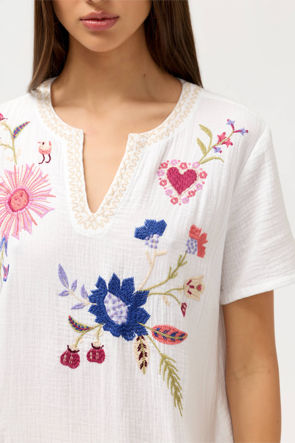 White blouse with colorful floral embroidery on a white background