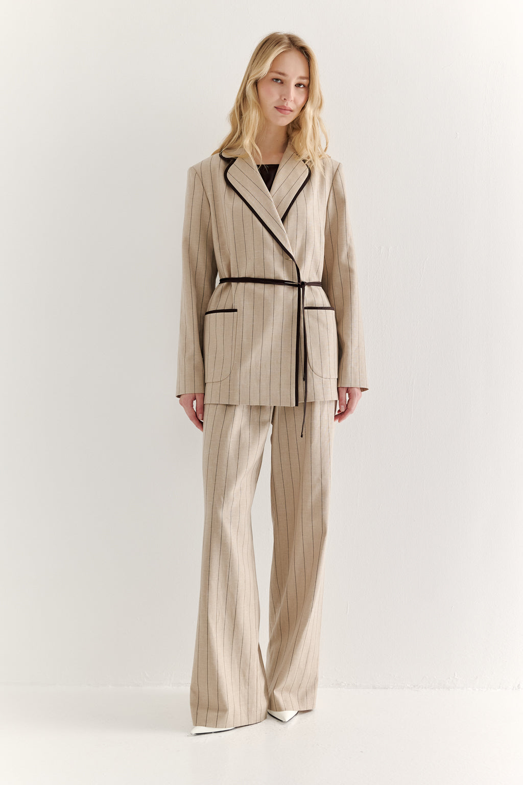 Woman wearing a beige and black striped suit on a white background
