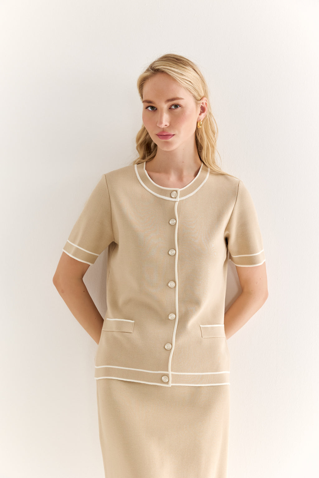 Woman wearing a beige uniform with white trim against a white background