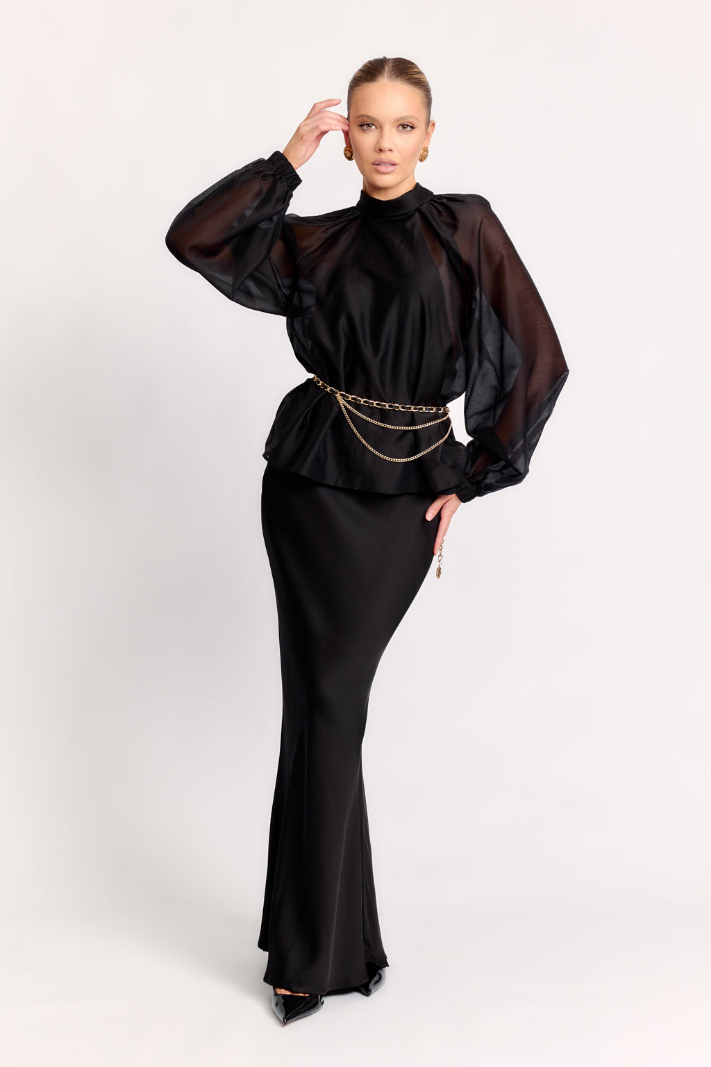 Woman wearing a black outfit with sheer sleeves on a white background