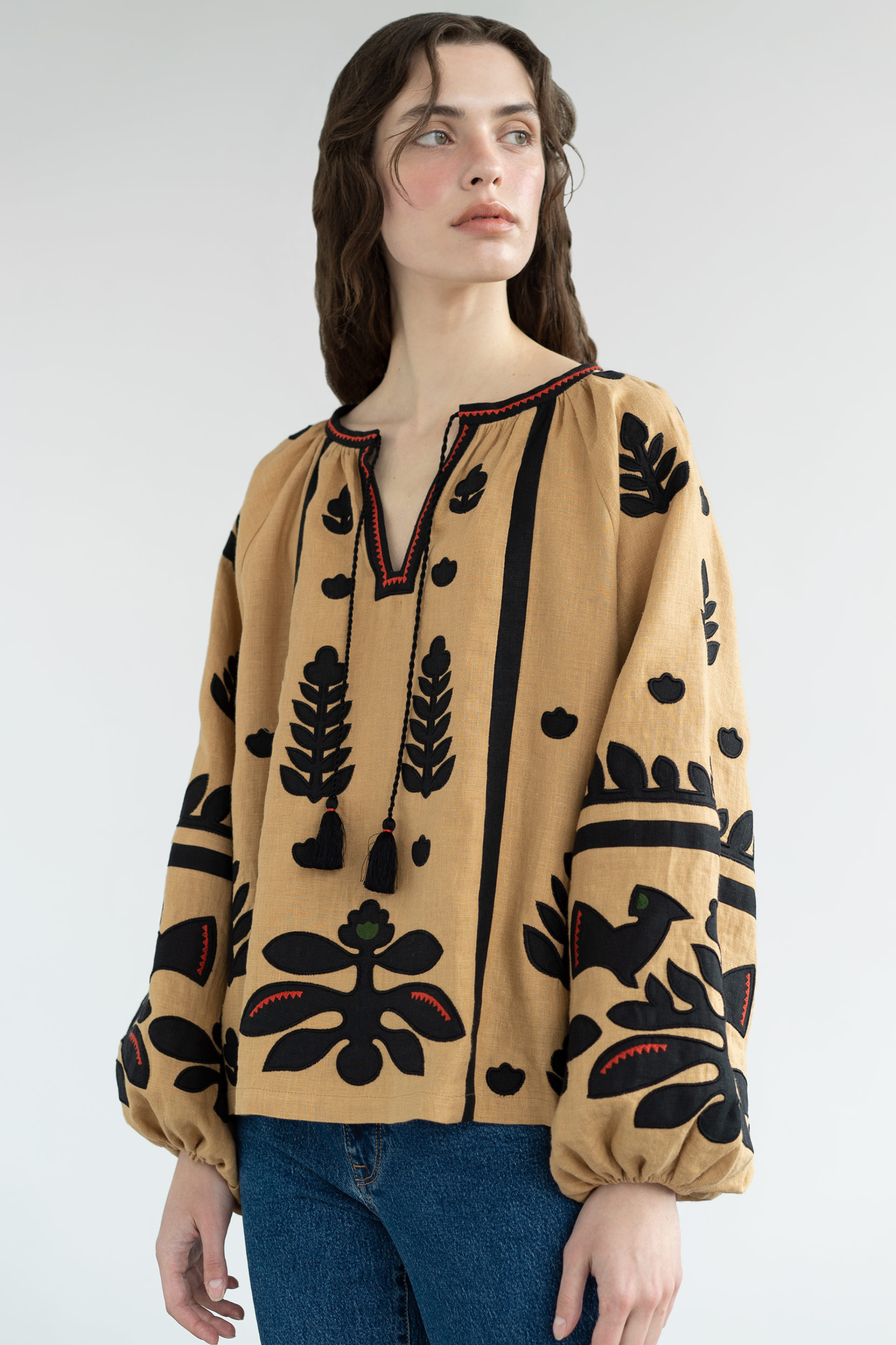 Woman wearing a beige blouse with black floral patterns on a white background