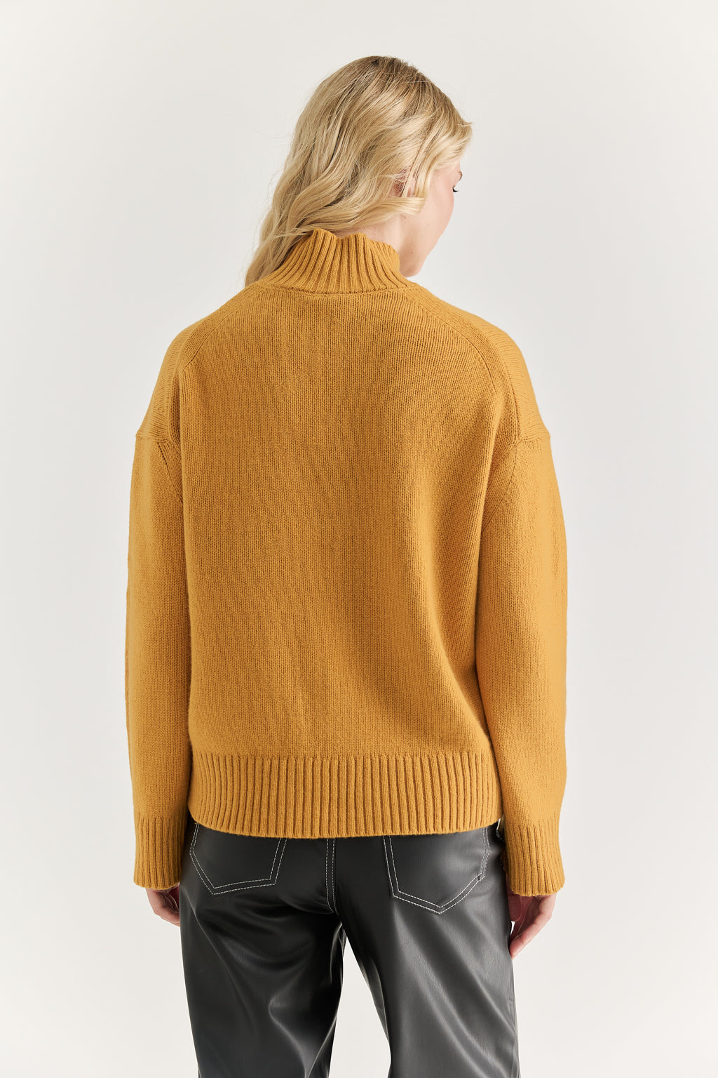 Person wearing a mustard yellow sweater on a white background