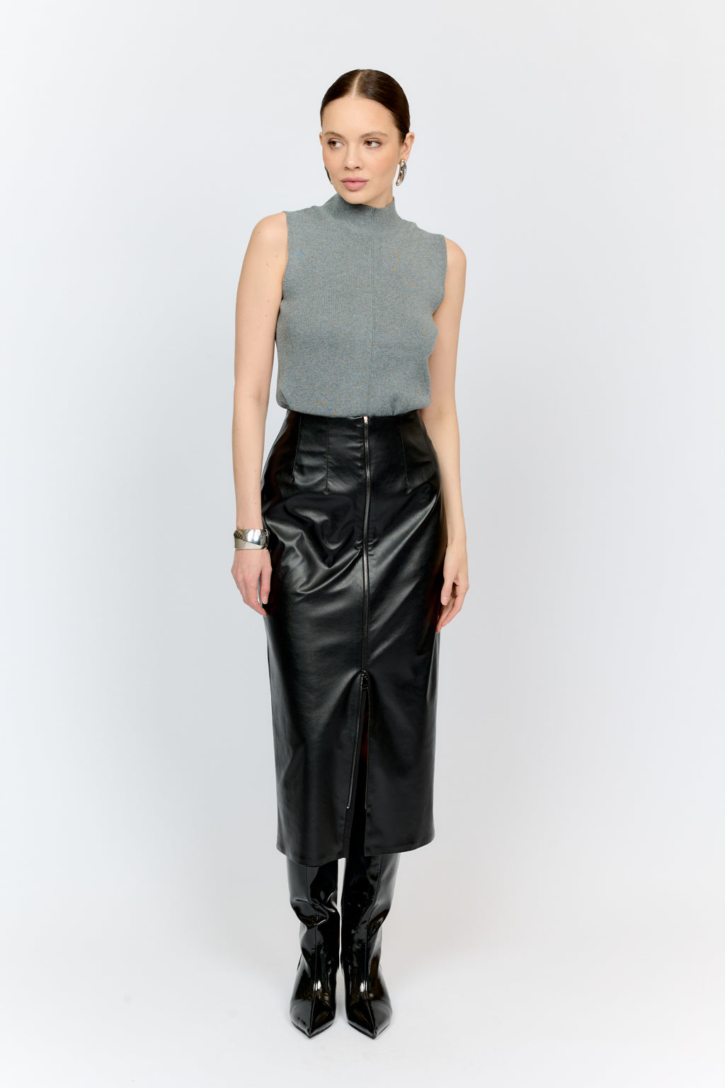 Woman wearing a gray sleeveless top and black leather skirt on a white background