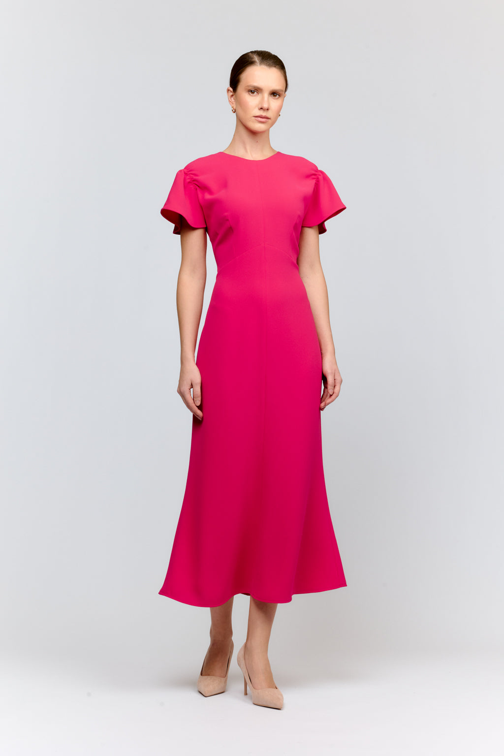 Woman wearing a bright pink dress on a white background