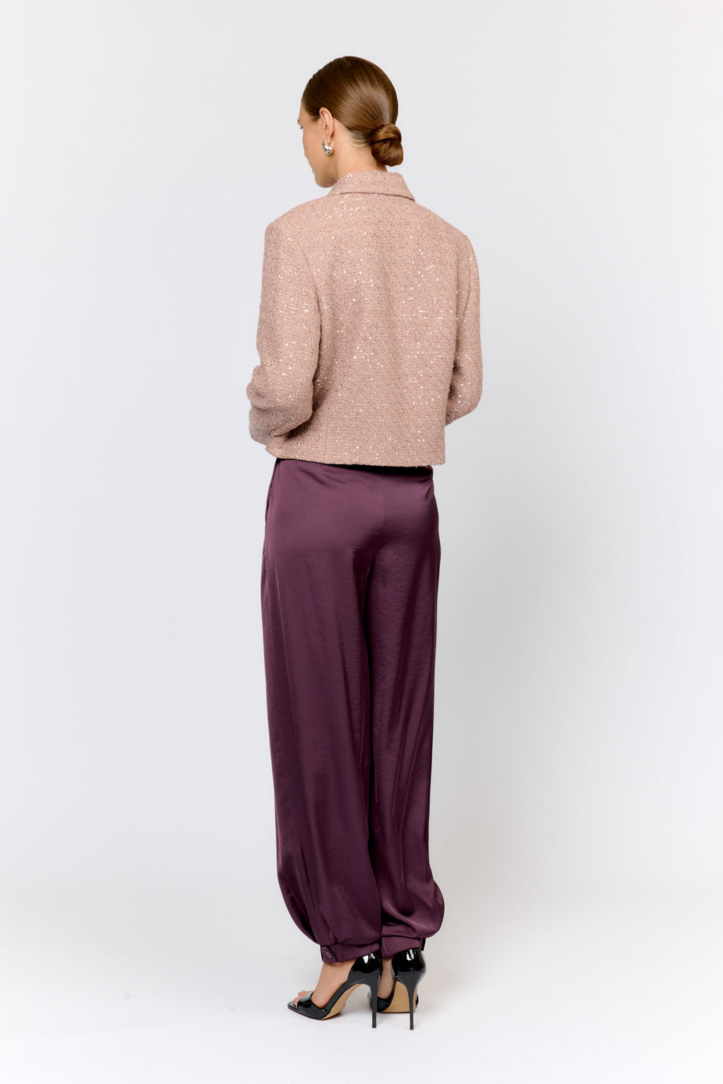 Person wearing a beige sweater and purple pants on a white background