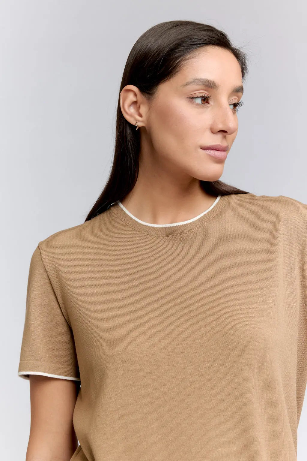 Woman wearing a beige top against a gray background