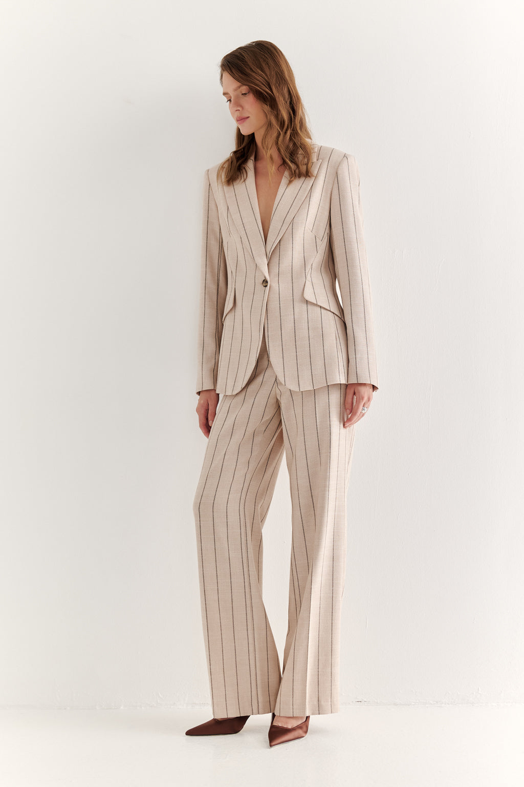 Woman wearing a beige pinstripe suit on a white background