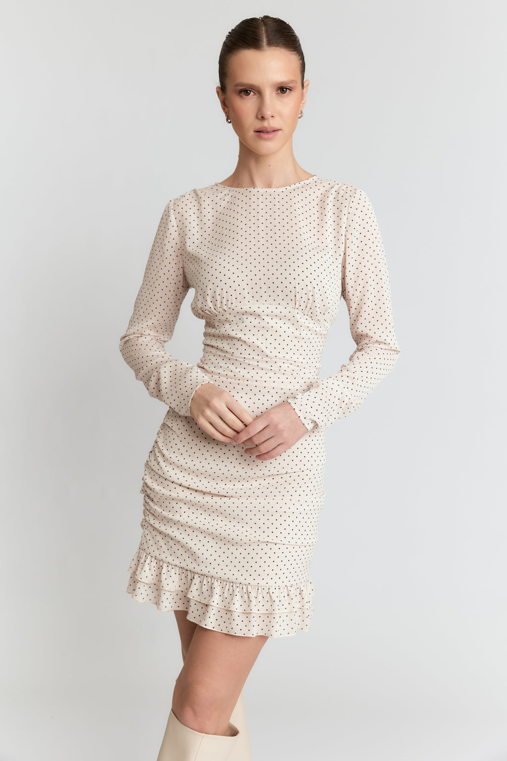 Woman wearing a beige polka dot dress on a white background