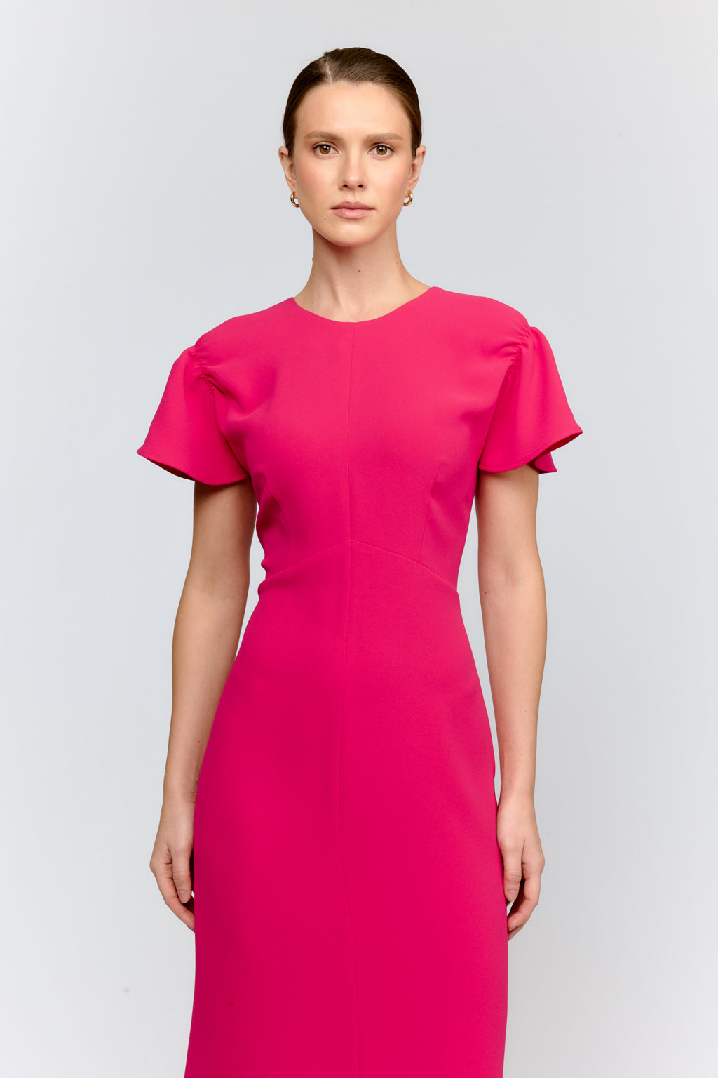 Woman wearing a bright pink dress against a light gray background