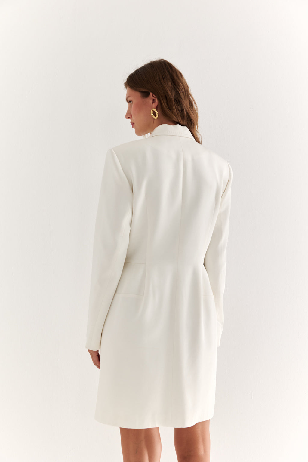 Woman wearing a white blazer against a plain background