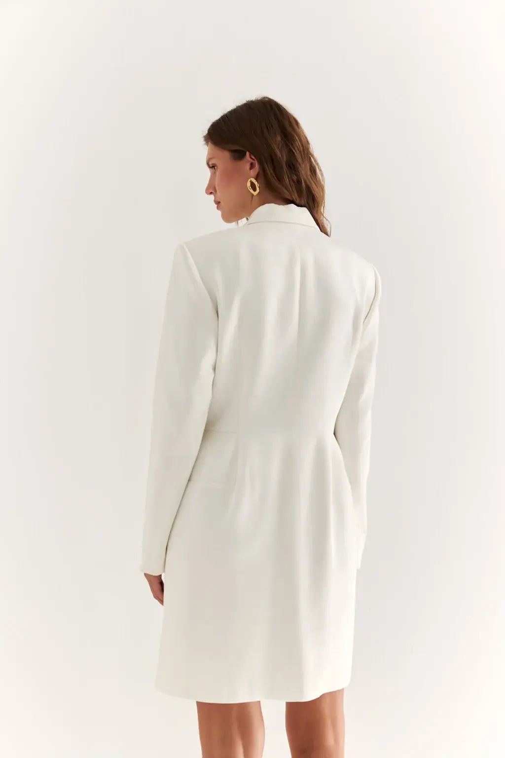 AYRA Store beautiful woman standing wearing  milk-colored double-breasted sculptural luxury jacket dress with architectural shoulders and hourglass silhouette