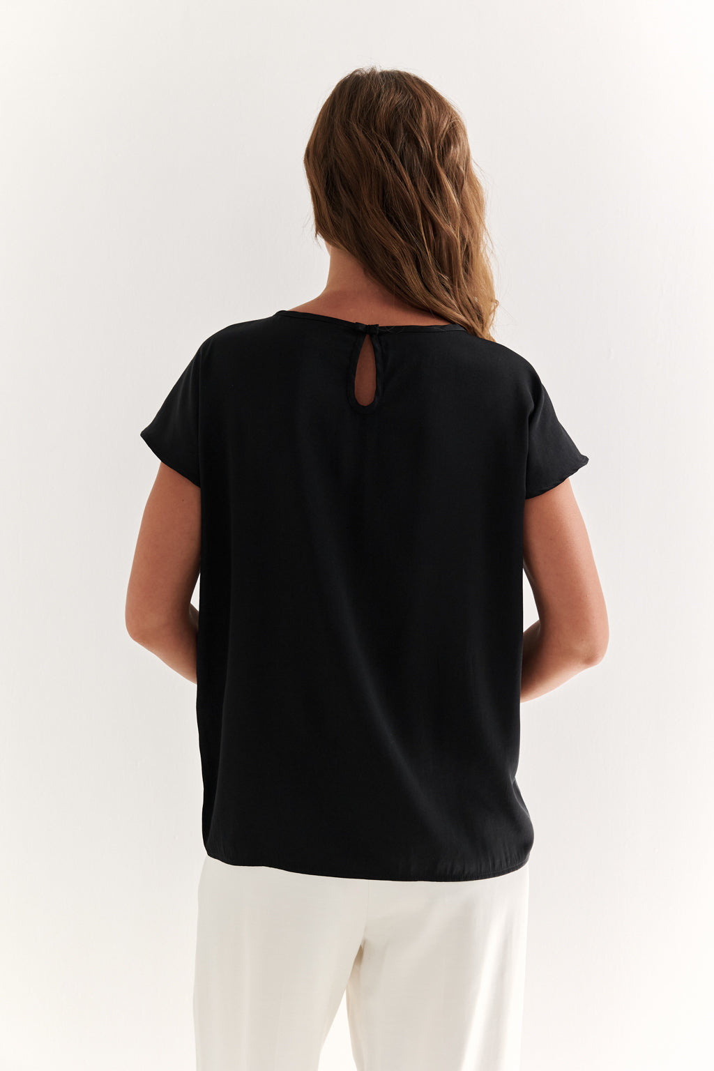 Person wearing a black t-shirt with a cut-out back design on a white background