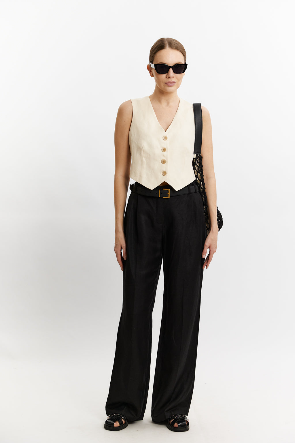 Woman wearing a white vest and black pants on a white background