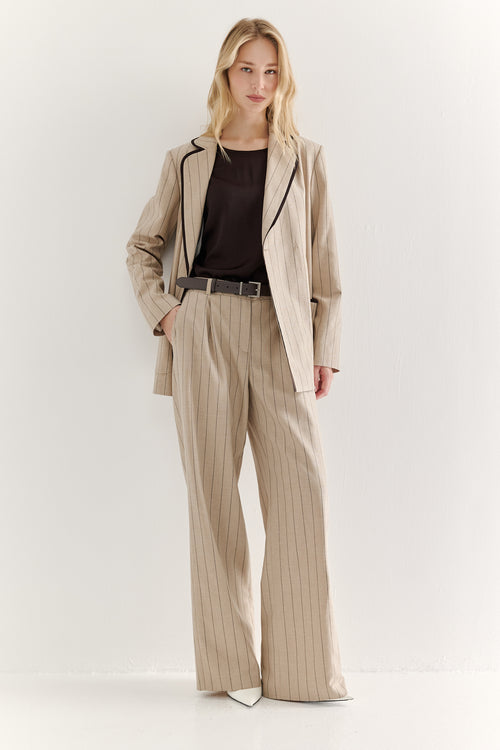 Woman wearing a beige suit with a black top on a white background