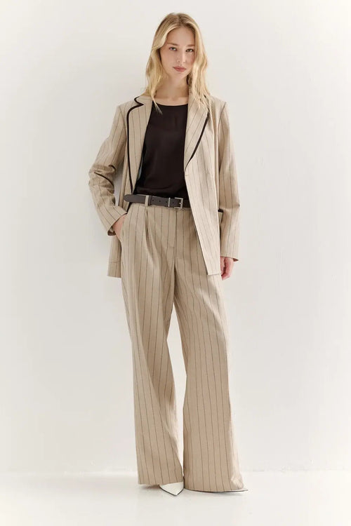 Woman wearing a beige suit with a black top on a white background