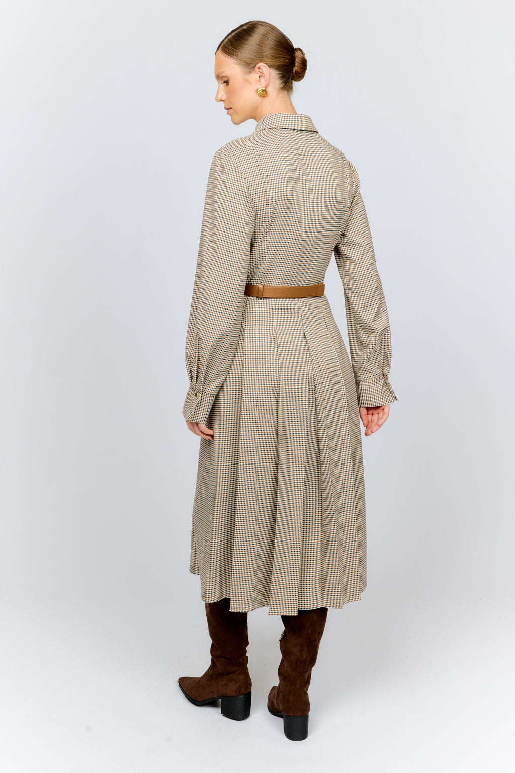Woman wearing a beige checkered dress with a belt on a white background