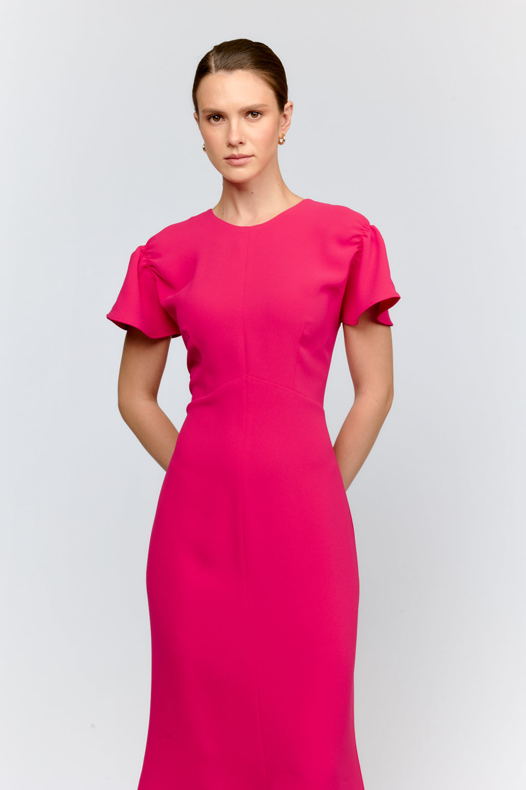 Woman wearing a bright pink dress on a light gray background