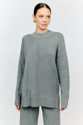 Woman wearing a gray sweater and pants on a white background