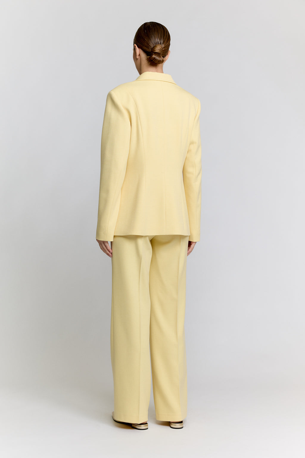 Person wearing a light yellow suit on a plain background